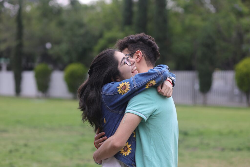 A man and woman are hugging each other in a park
